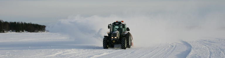 Traktor med snöslunga plogar isvägen